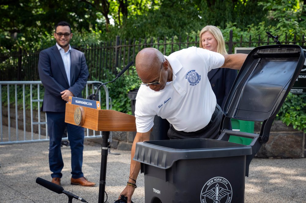 Mayor Eric Adams shows off one of the city's new trash bins.