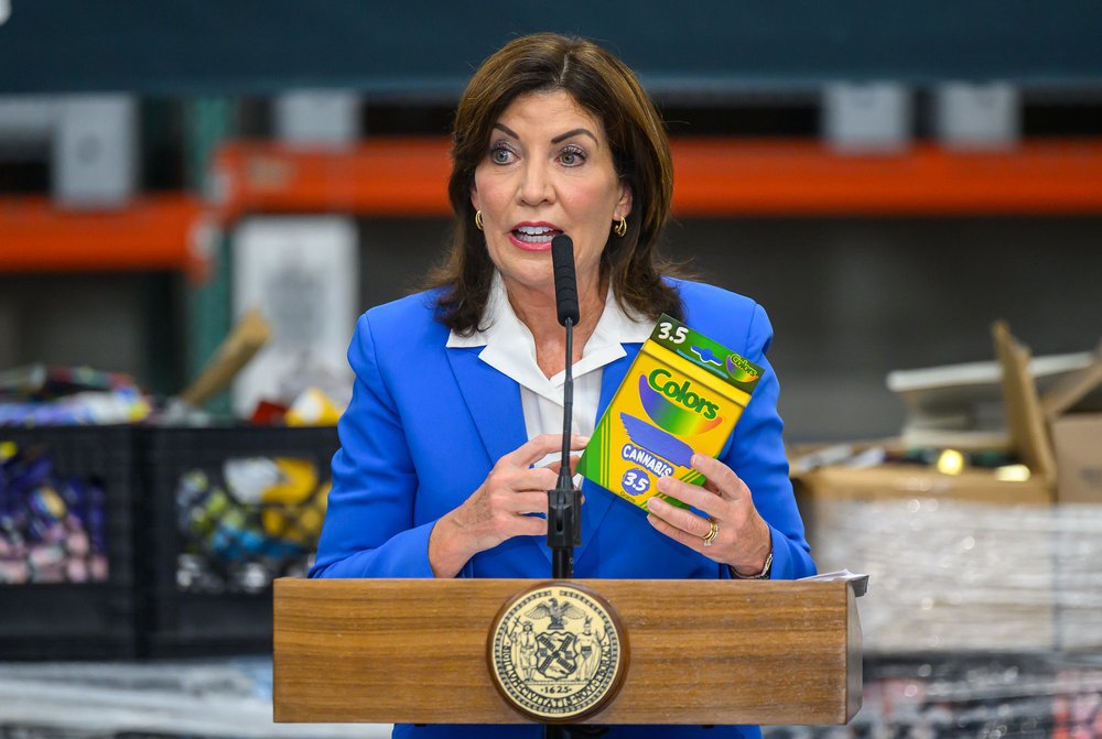Gov. Kathy Hochul holds a box of what looks like Crayola crayons, except it's a marijuana packaging.