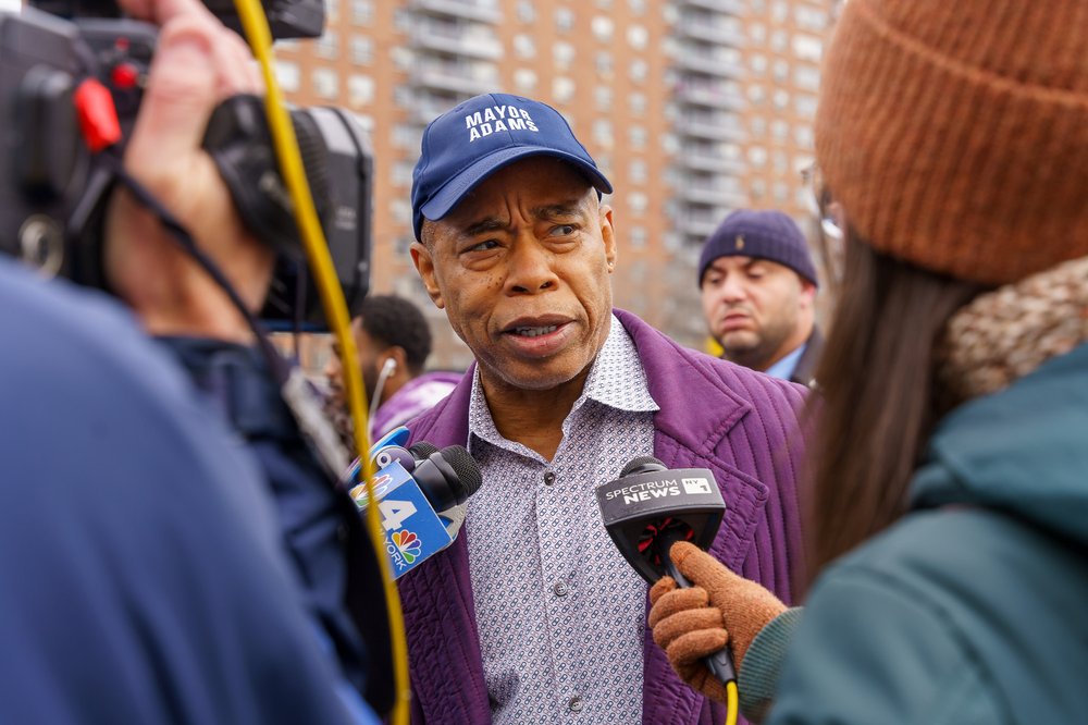 Mayor Eric Adams confronted with two microphones