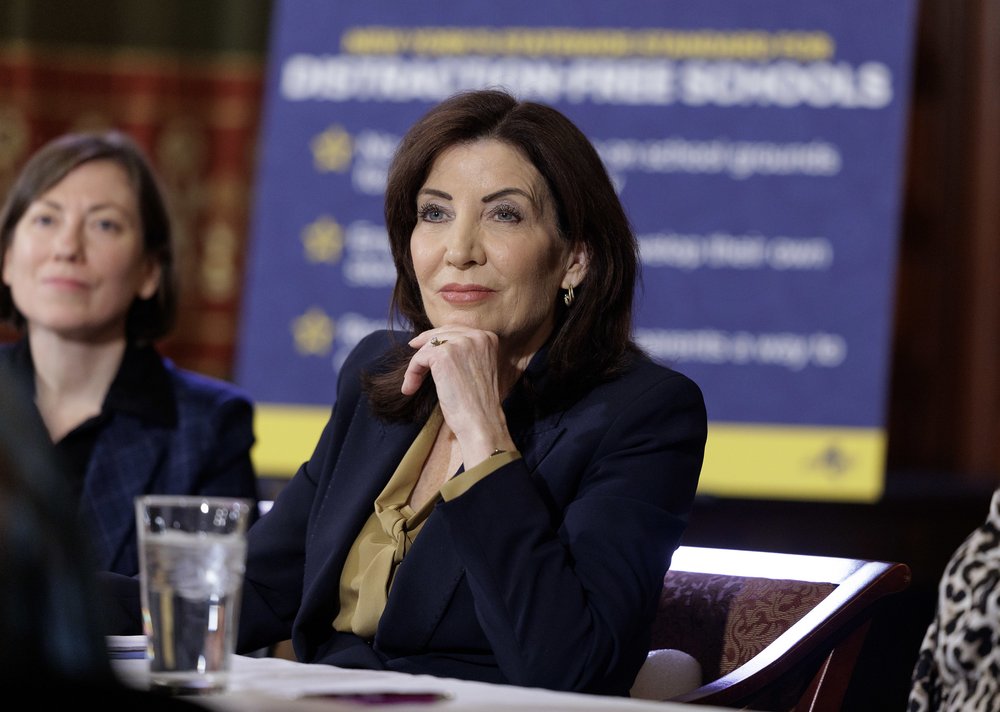 Gov. Kathy Hochul in front of a poster that says DISTRACTION-FREE SCHOOLS