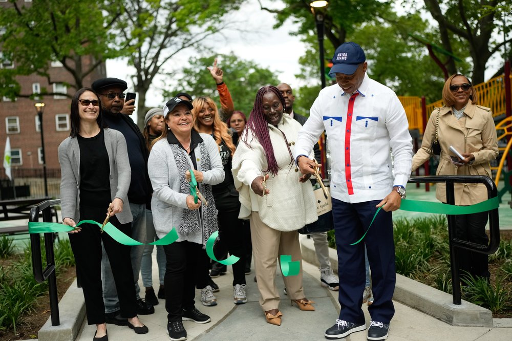 Iris Rodriguez-Rosa cuts a ribbon on her first day as New York City parks commissioner. She stands next to Mayor Eric Adams and other officials. Everyone is smiling. Rodriguez-Rosa has spent decades working in city government.
