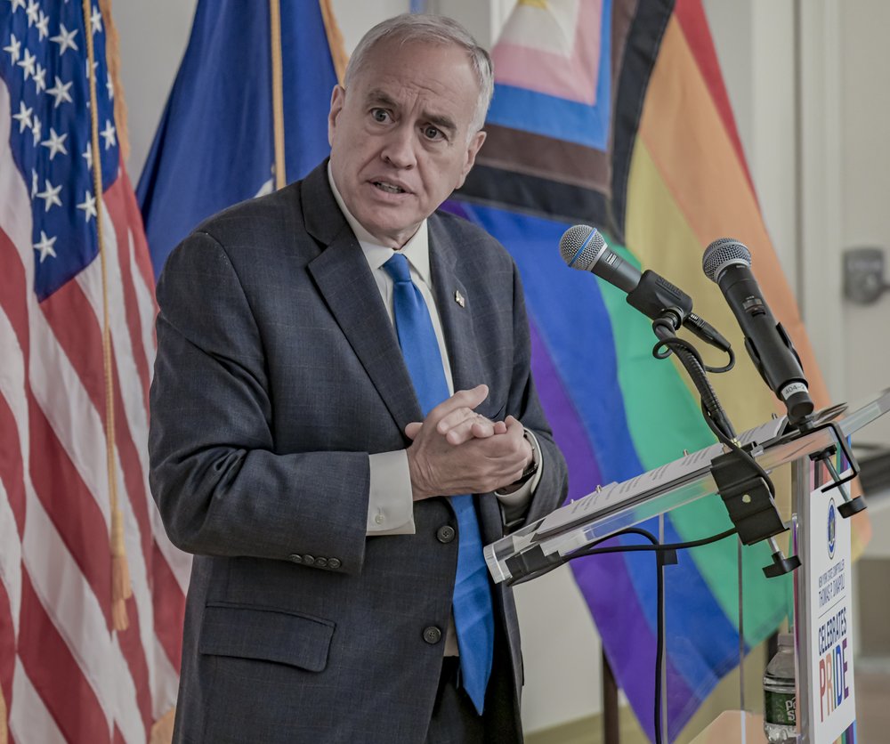 A man speaks at a podium at a Pride celebration.