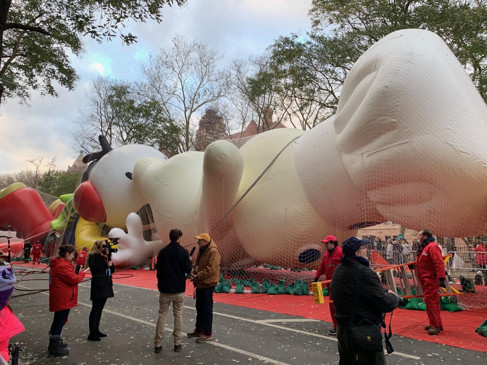 56c54c7f6img_0764-jpg.jpeg John Piper (in yellow cap), vice president of Macy's Parade Studio, speaks to a reporter. (Jen Chung / Gothamist)
