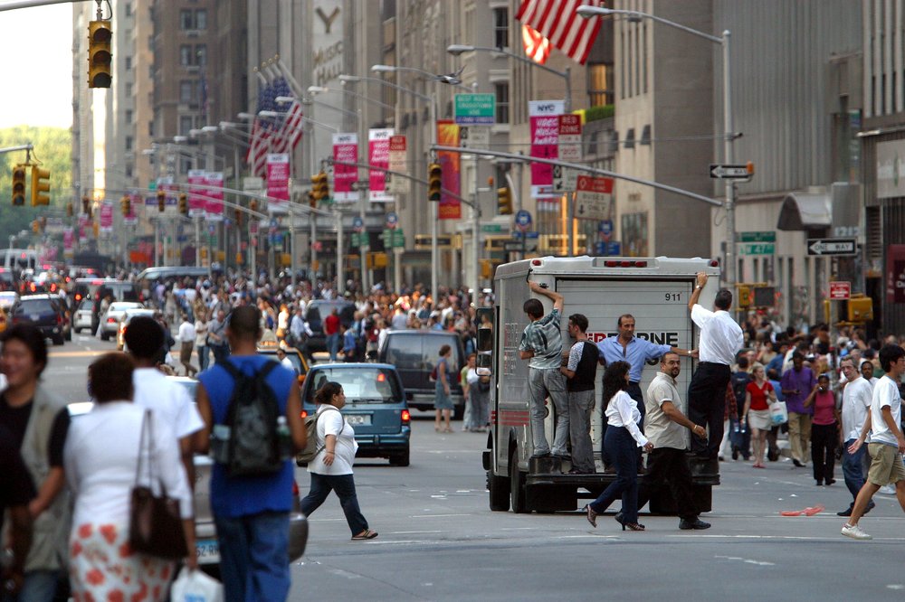 People hitch a ride on the back of a van, August 14, 2003 (Shutterstock)