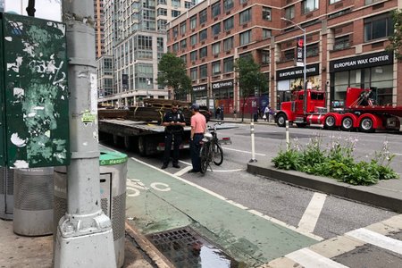 An NYPD officer tickets a cyclist on 6th Avenue just north of West 24th Street, where bike messenger Robyn Hightman was killed by a hit and run truck driver on Monday morning.