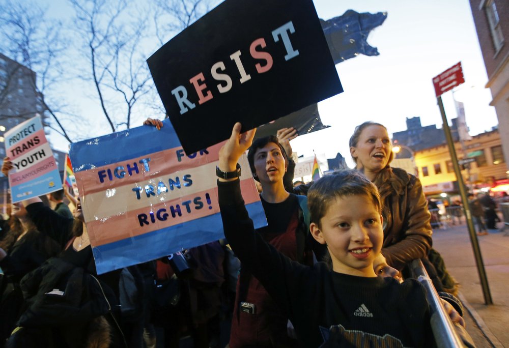 62ebc3489transgender-rally_chun-4-jpg.jpeg Tal Moskowitz, 8, below, a transgender child, holds a sign as his parents Faigy Gelbstein, left, and Naomi Moskowitz, upper right, of Long Island, hold separate signs during a rally in support of transgender youth at the Stonewall National Monument, Thursday, Feb. 23, 2017 (Kathy Willens / AP)