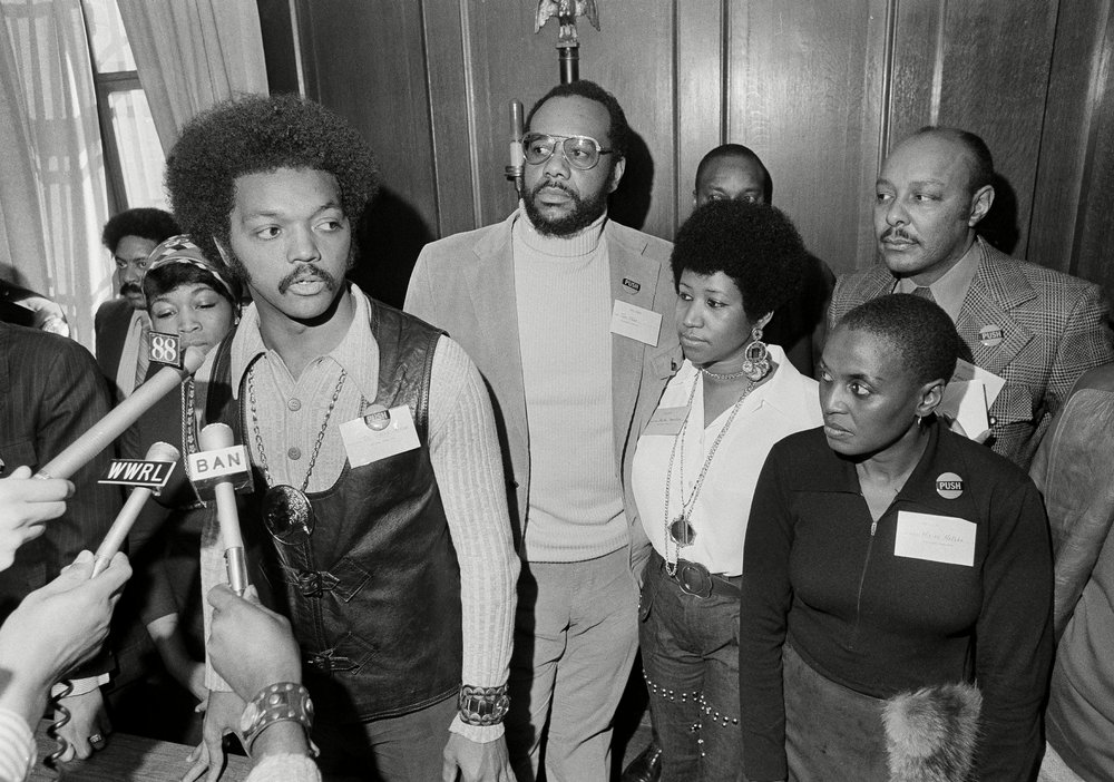 807505e30shutterstock_5946177c-jpg.jpeg Jesse Jackson, Betty Shabazz, Tom Todd, Aretha Franklin, Miriam Makeba, Louis Stokes Rev. Jesse Jackson speaks to reporters at the Operation PUSH Soul Picnic at the 142nd Street Armory in New York, . Left to right are: Betty Shabazz, widow of Malcolm X; Jackson; Tom Todd, vice president of PUSH; Aretha Franklin; Miriam Makeba and Louis Stokes, rear right. PUSH stands for People United to Save Humanity <br>(Jim Wells/AP/Shutterstock)