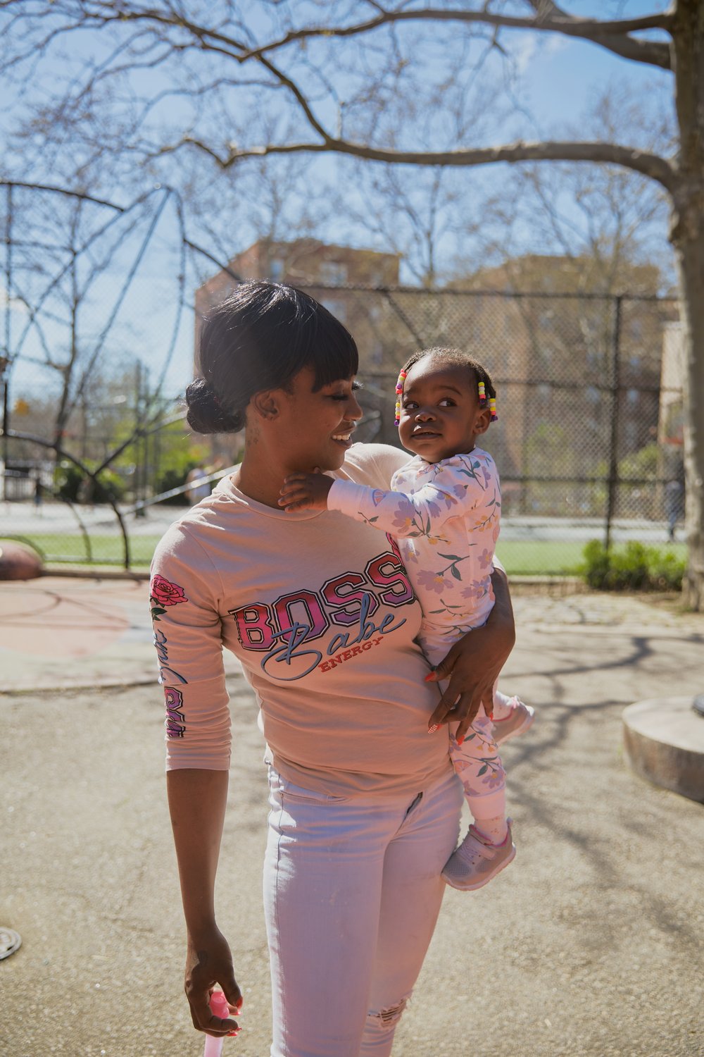 A woman holds her infant daughter, and smiles at her.