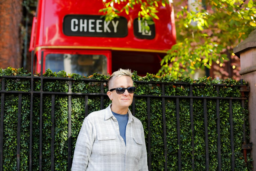A woman standing in front of a fence in Chelsea.