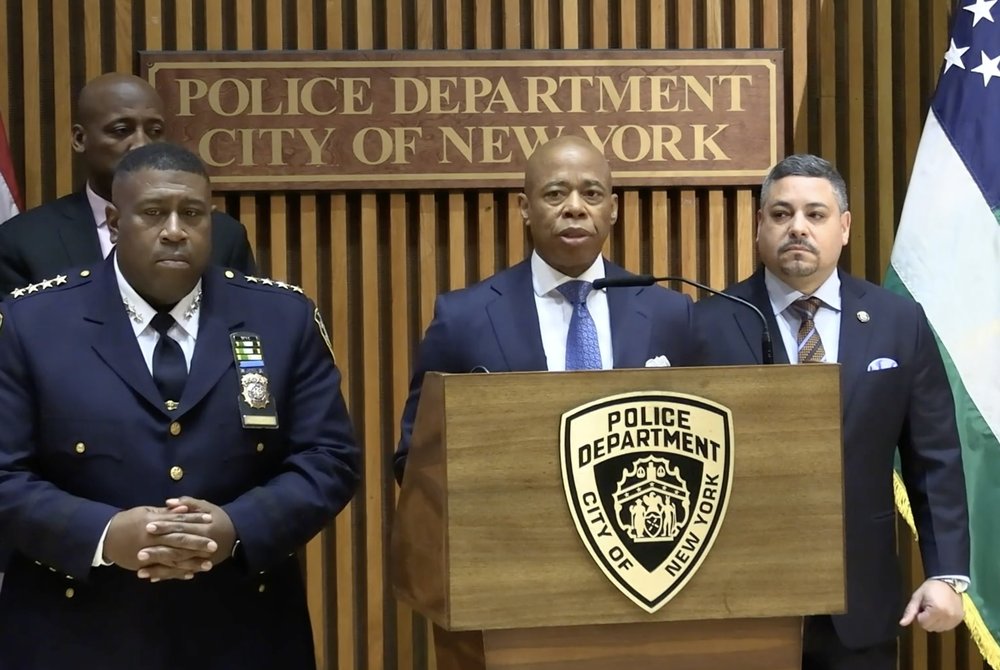 A photo of Mayor Eric Adams and police officials briefing reporters on the arrest of a suspected serial stabber in Queens.