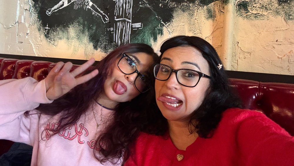 A photo of Stephanie Rodas laughing and smiling on a couch with her mom, Diana Agudelo.