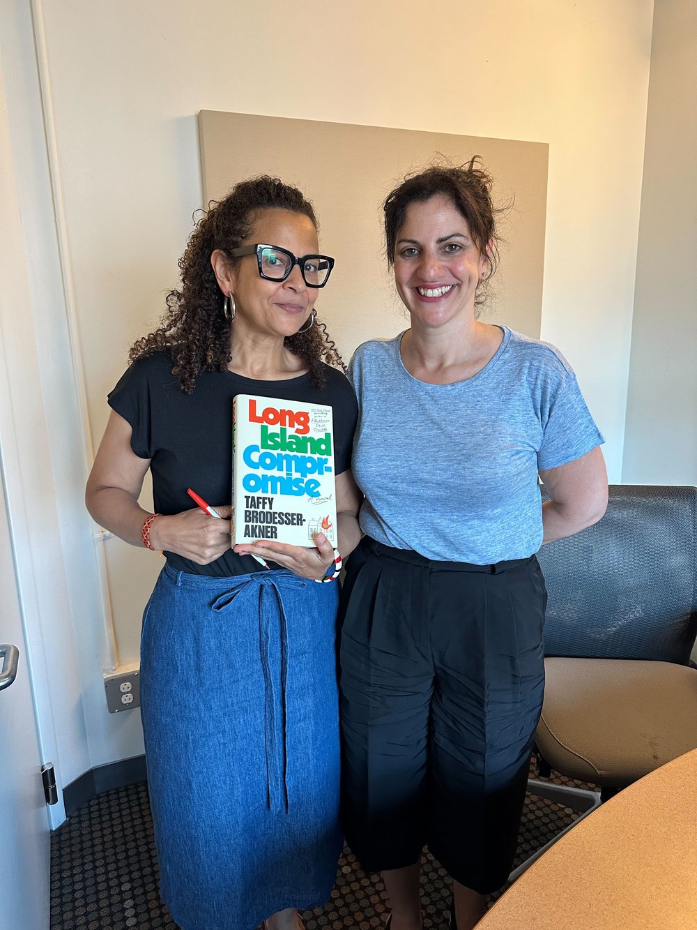 Two women pose with a book that says "Long Island Compromise."