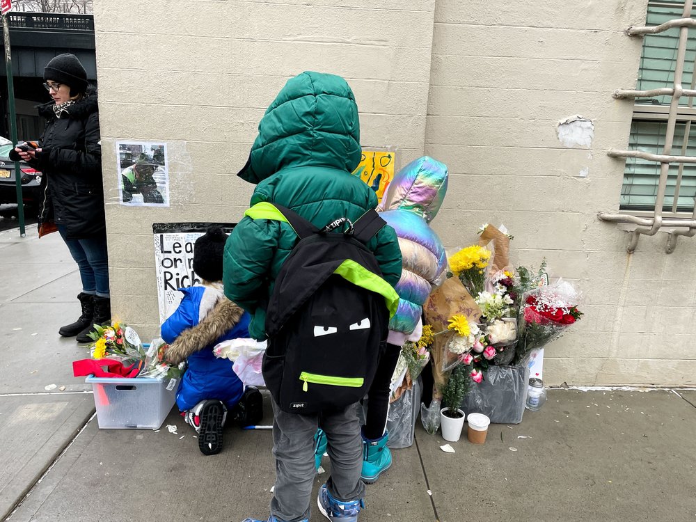 Children near a memorial on the side of a building.