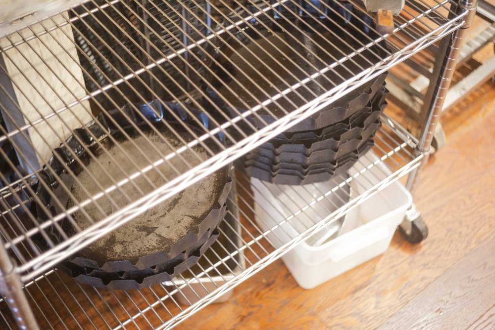 pizza pans stacked on a shelf in a kitchen