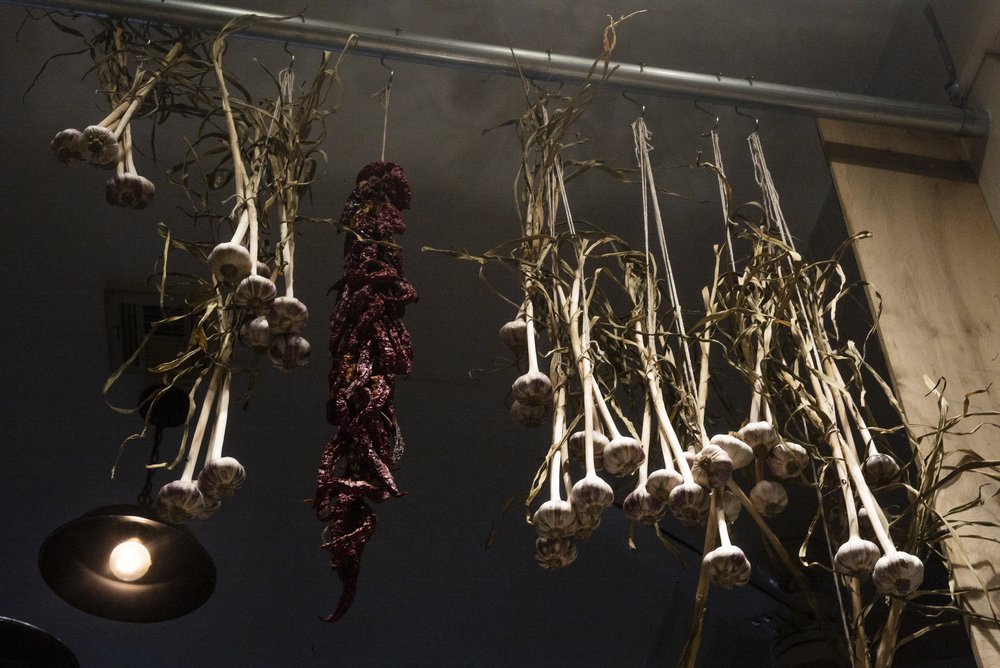 Dried garlic, peppers and onions hanging from a rack