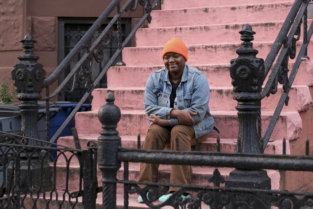 A woman sits on a pink stoop.