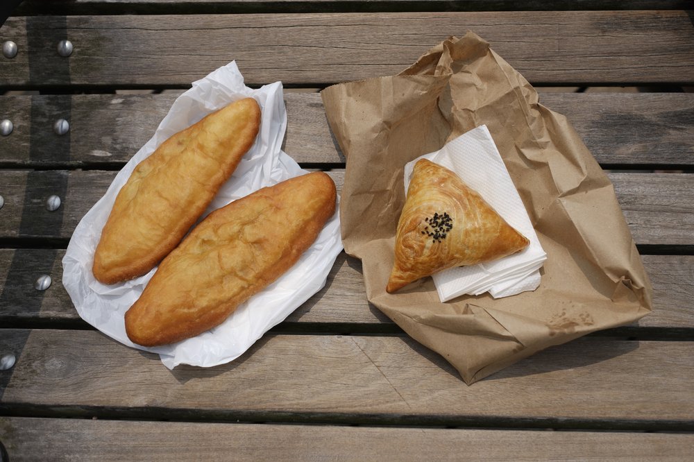 Two flaky treats on paper plates, on a bench.