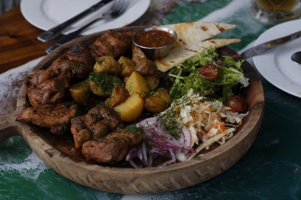 A large plate filled with cubes of grilled pork, and seasoned potatoes.