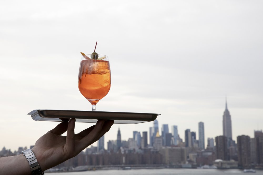 A beverage glass held aloft in front of a city skyline