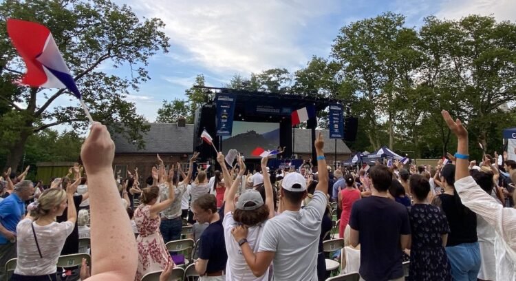 a group of people wave French flags in front of a screen