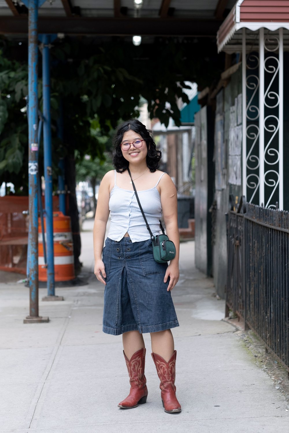 A person wears a denim skirt and boots