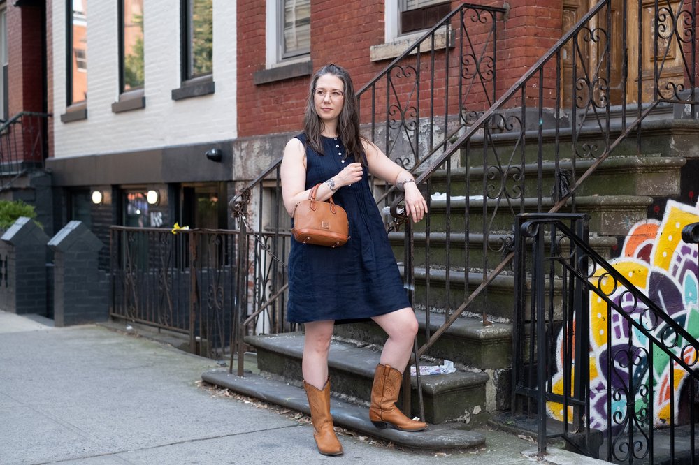 A person wears boots and a navy dress in New York City.