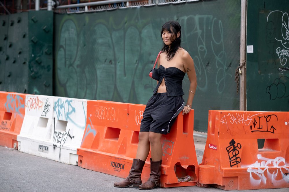 A person wears boots while sitting against a construction barrier.