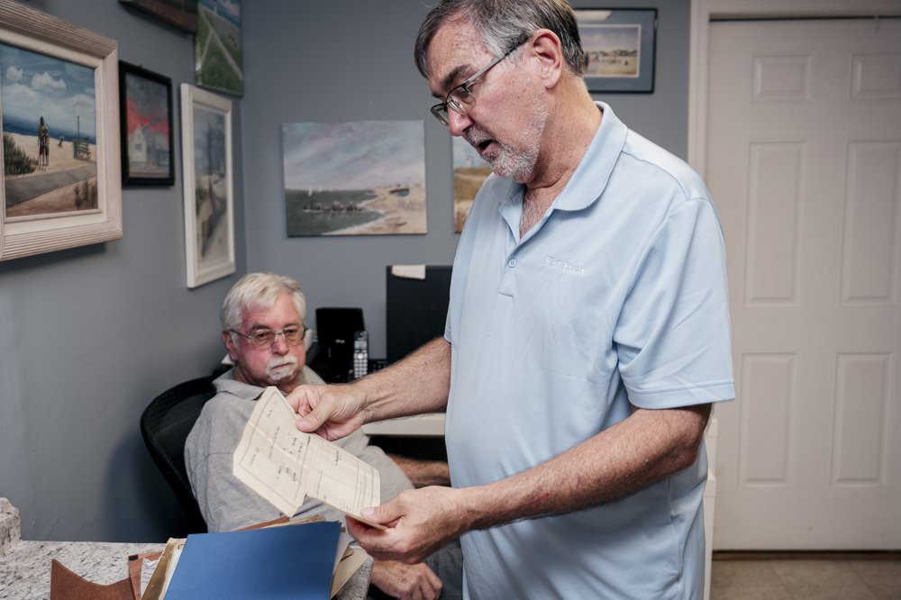 Breezy Point Historical Society curator Paul Balukas looks through a collection of old community records with treasurer Arthur Lighthall (seated).