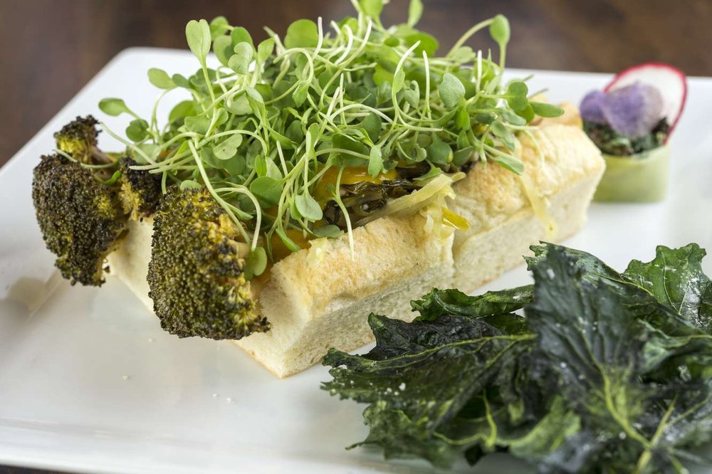 A food dish featuring broccoli wrapped in bread and topped with sprouts