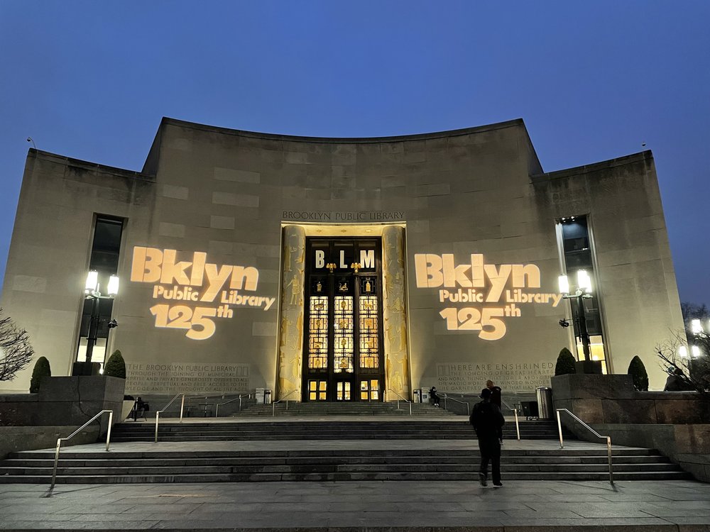 A photograph of the main branch of the Brooklyn Public lit up at night