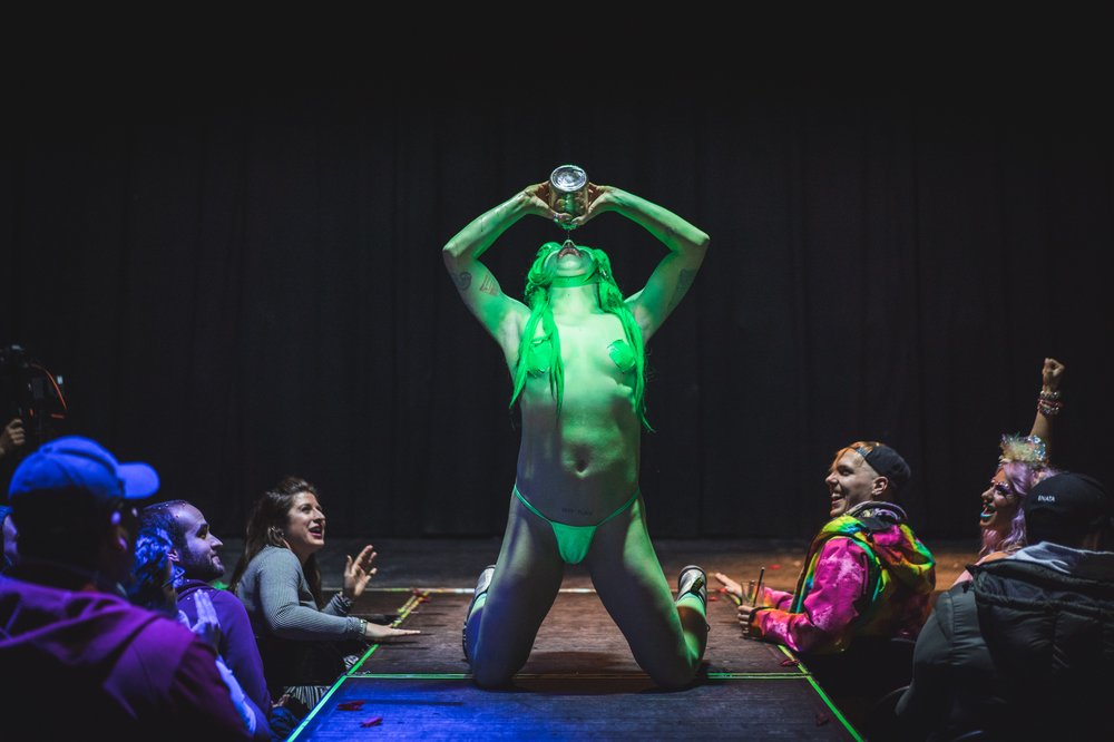 A person dances on a stage wearing a green thong.