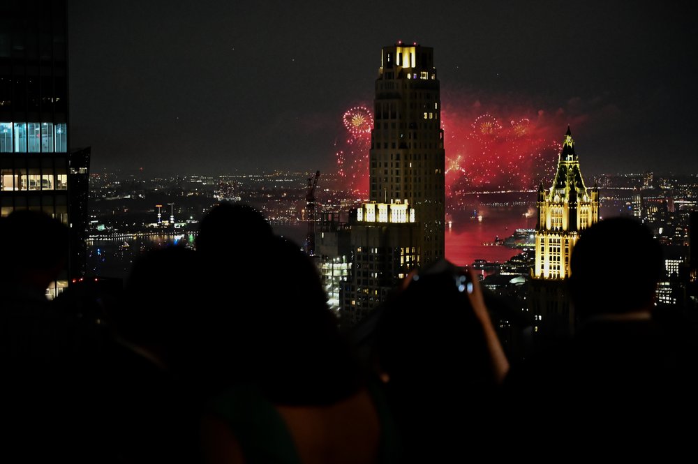 Fireworks exploding in the sky behind a skyscraper.