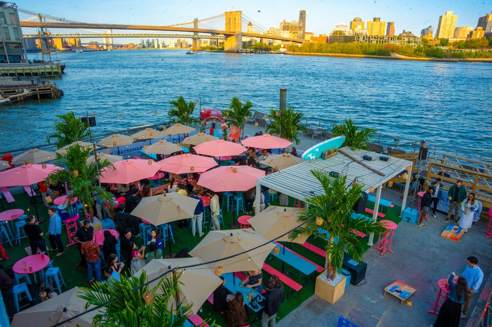 A few of tables and chairs with the Brooklyn Bridge in the background.