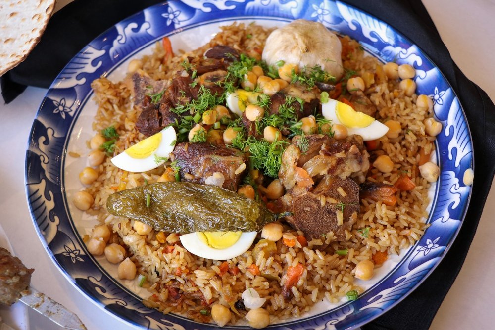 A blue and white bowl filled with rice and chickpeas and other foods.