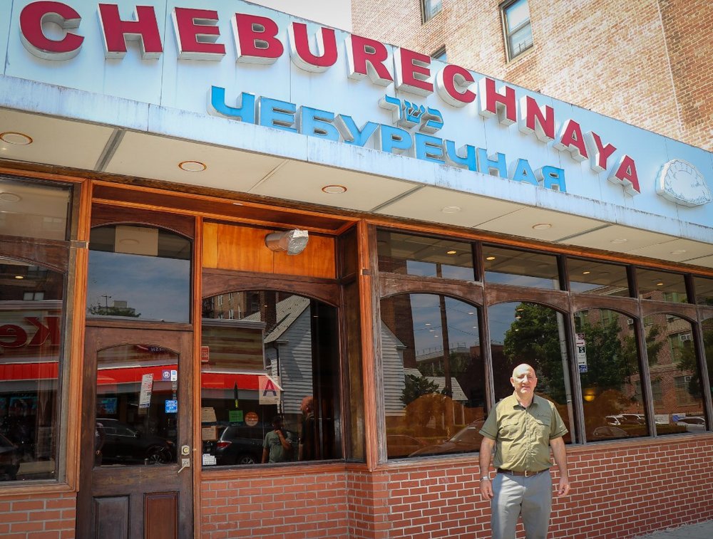 A man stands in front of a restaurant