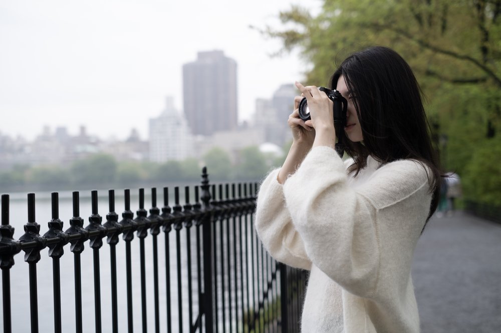 A woman outside holds a camera