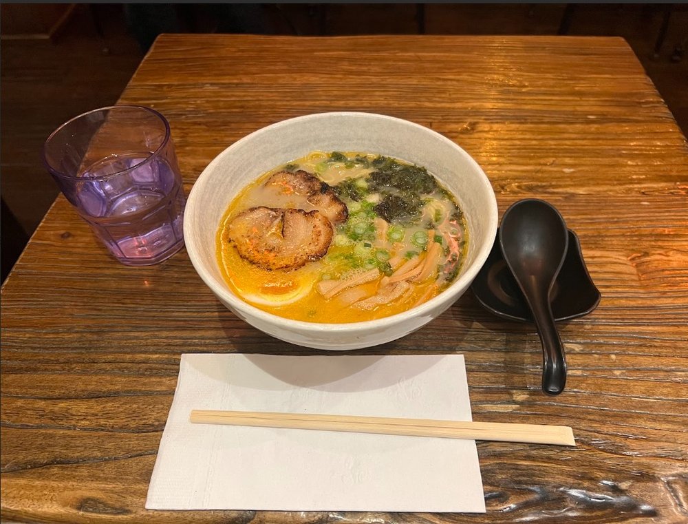 A bowl of soup with chopsticks placed in front.