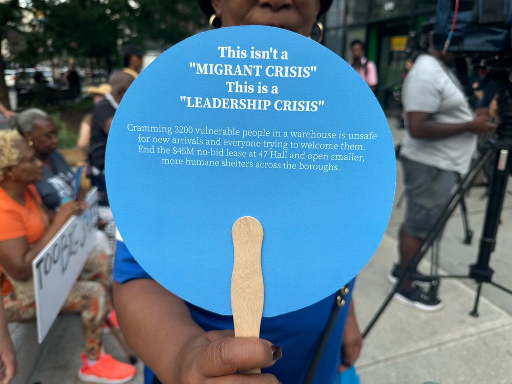 Protester with a fan makes the case against a mega shelter for migrants in Clinton Hill, near the Brooklyn Navy Yard.
