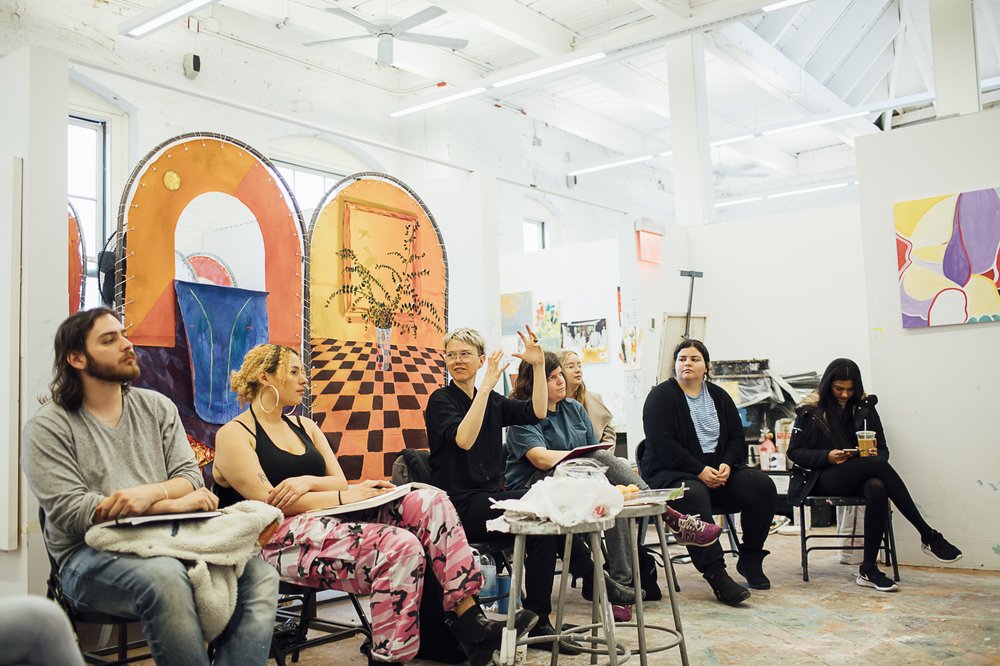 A group of people sit in desks in a classroom.