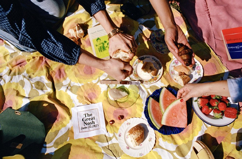 A group of people reach for food on a table.
