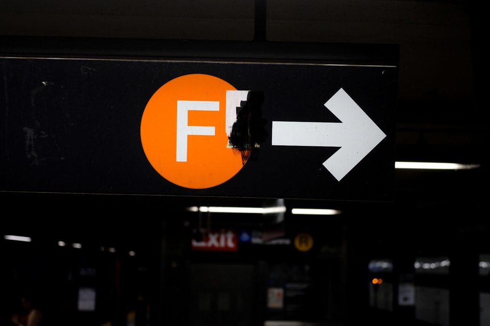 A broken subway sign for the F train.