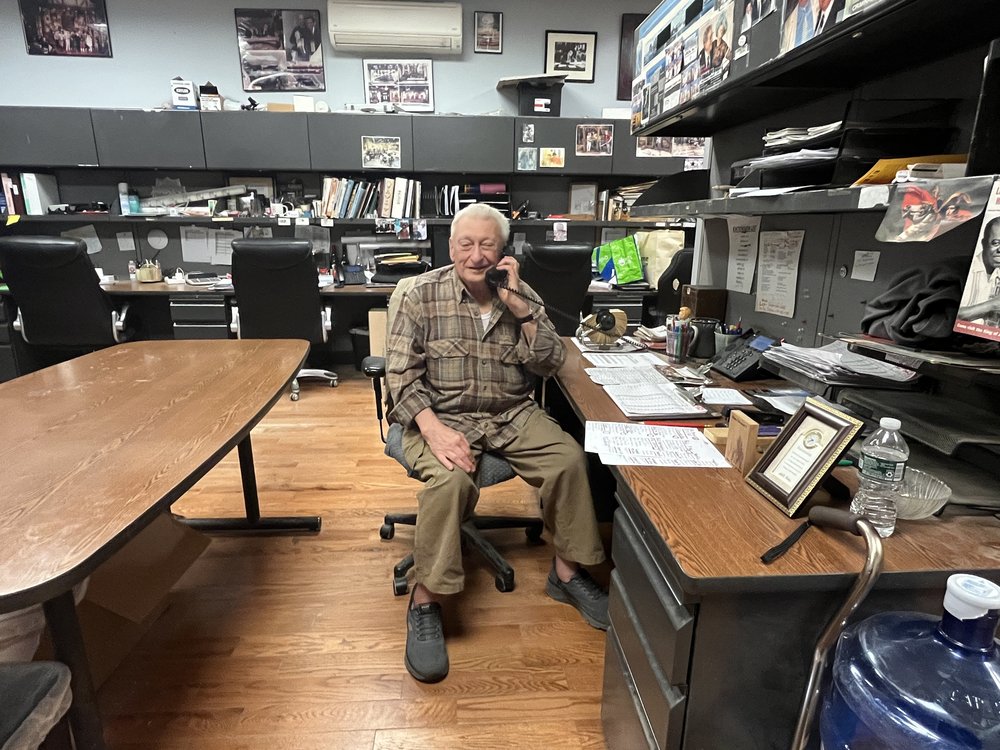 A man sits at a desk in a workshop.