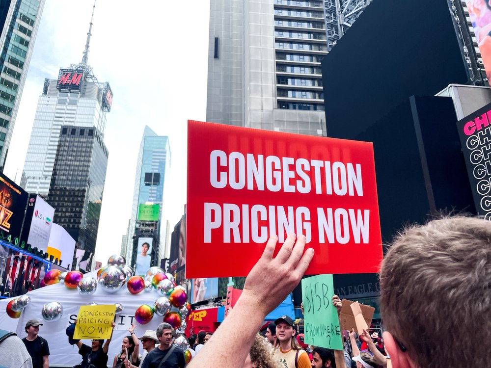 Protesters holding signs in favor of congestion pricing in Columbus Circle.