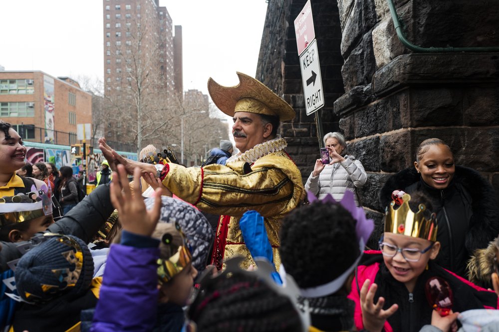 A man dressed as a biblical king greets a crowd of children with high-fives.