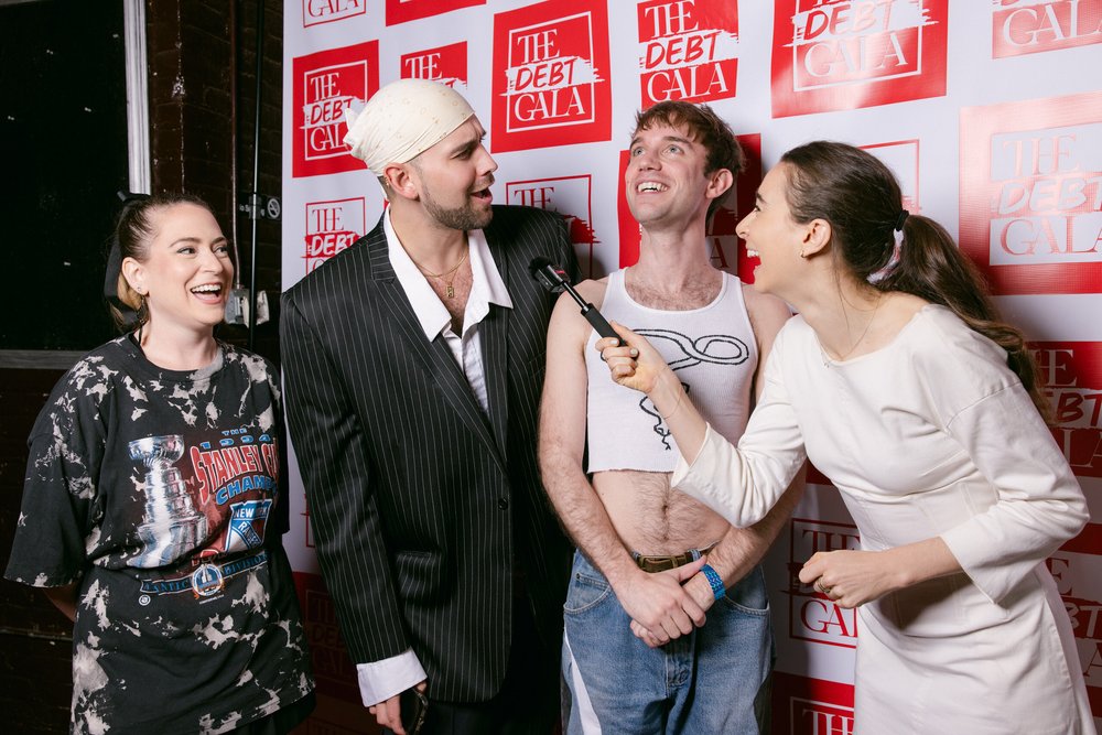 Four people stand against a red and white wall.
