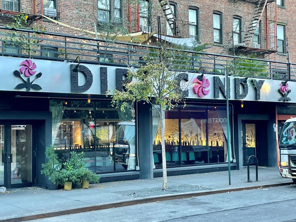 A Manhattan storefront restaurant with small trees in front of it.