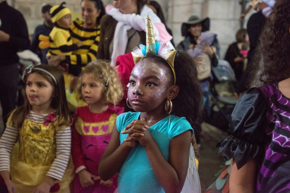A girl with a blue ballerina costume stands in a crowd on Halloween