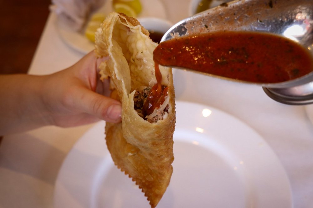A puff pastry with red sauce being poured into it