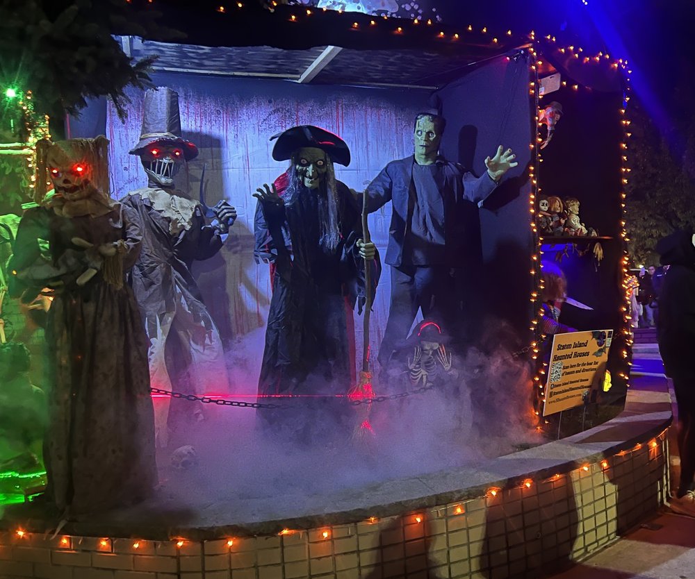 A display of a witch in front of a house at night.