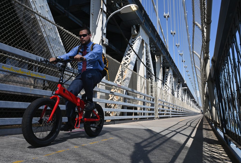 A stock image of someone riding an e-bike over the Manhattan bridge.